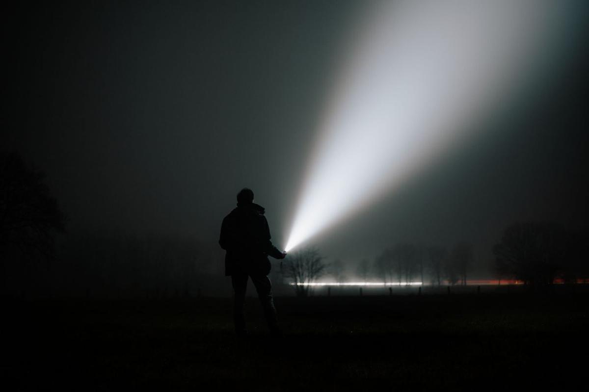 Security officer patrolling a site at night with a torch